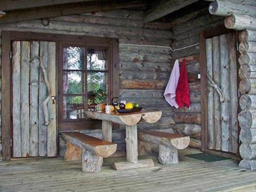 a wooden cabin with a table and benches in it at Holiday Home Mäntyniemi by Interhome in Pätiälä