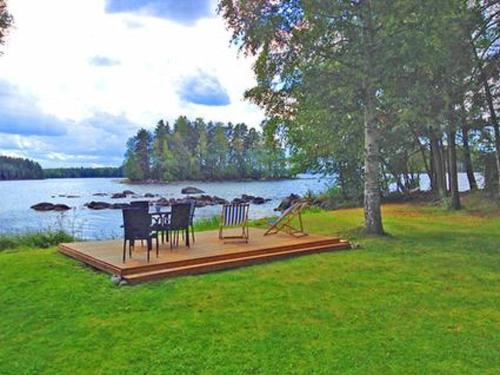 a table and chairs sitting on a deck next to a lake at Holiday Home Kivilahti by Interhome in Iltasmäki