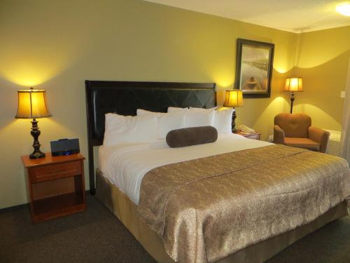 a hotel room with a large bed and a chair at Village Creek Country Inn in Westerose