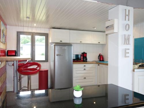 La cuisine est équipée d'un réfrigérateur et d'un tabouret rouge. dans l'établissement Chalet Le Bois d'Amour by Interhome, à Dinard