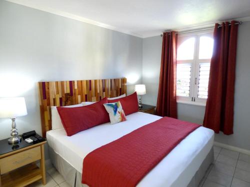 um quarto com uma cama com lençóis vermelhos e uma janela em Beach One Bedroom Suite A17 em Ocho Rios
