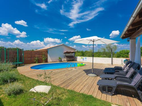 a deck with chairs and an umbrella next to a pool at Holiday Home Stefanina by Interhome in Labin
