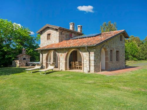 ein Steingebäude mit zwei Bänken im Gras in der Unterkunft Holiday Home Casale Fonte by Interhome in Roccastrada