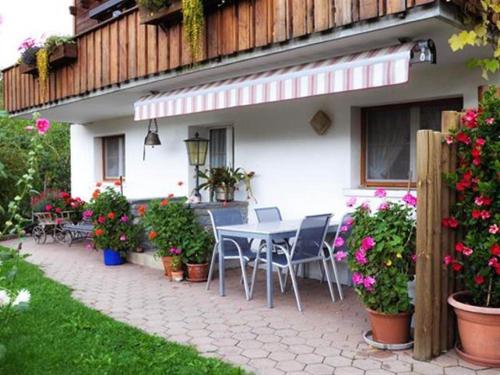 a patio with a table and chairs and flowers at Apartment Christeli by Interhome in Zweisimmen