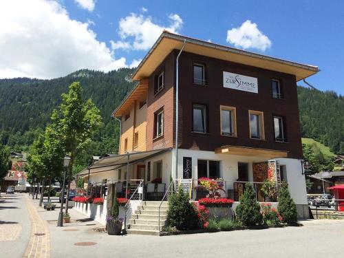 a large brown building with flowers in front of it at Apartment Simme-Tröimli by Interhome in Zweisimmen