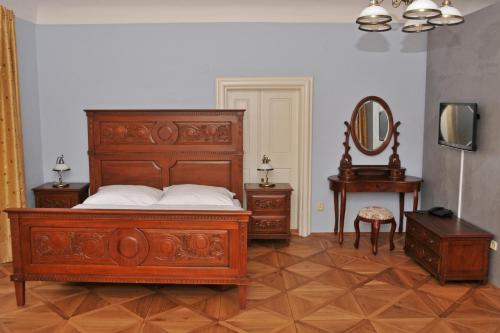 a bedroom with a large wooden bed and a mirror at Penzion na Faře in Dubenec