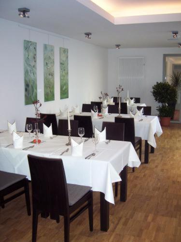a dining room with white tables and black chairs at Akzent Hotel Deutsche Eiche in Uelzen
