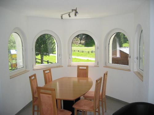 サースフェーにあるHoliday Home Haus Alpenstern- Wohnung Trift by Interhomeのアーチ型の窓、テーブル、椅子が備わるダイニングルーム