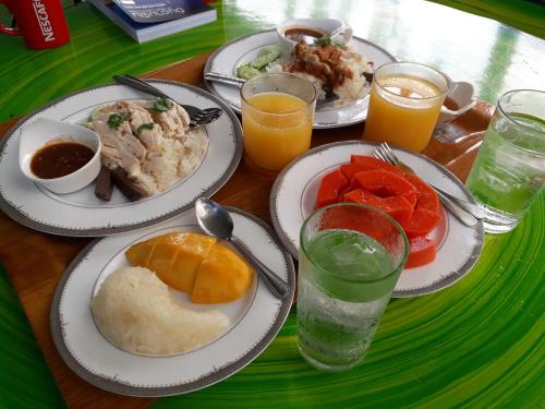 a table with plates of food and glasses of orange juice at Baan Glangsuan Bang Kobua in Bang Chak