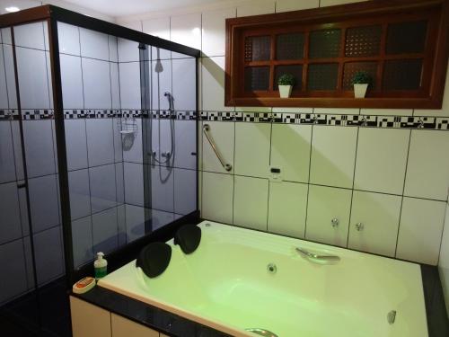 uma casa de banho com uma banheira verde e um chuveiro em Chalés Recanto Pássaros em Monte Verde
