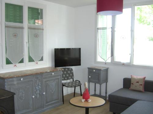 a living room with a couch and a tv at Holiday Home Maison Les Oies by Interhome in Blot-lʼÉglise