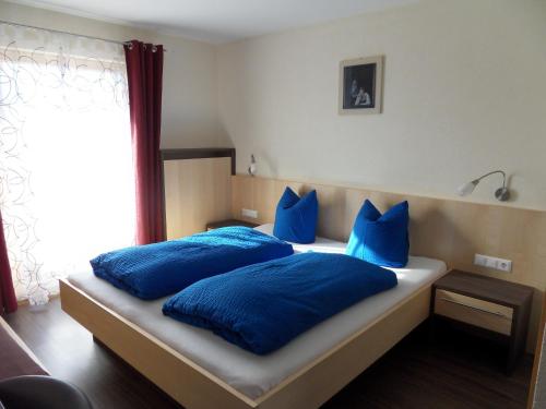 1 dormitorio con almohadas azules en una cama con ventana en Haus Erhart, en Ladis