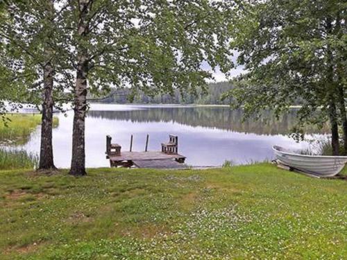 un banc à côté d'un lac avec un bateau dans l'établissement Holiday Home Alahuone by Interhome, à Pätiälä