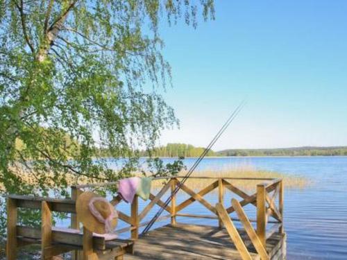 a person sitting on a bench next to a body of water at Holiday Home Peltotupa by Interhome in Pätiälä