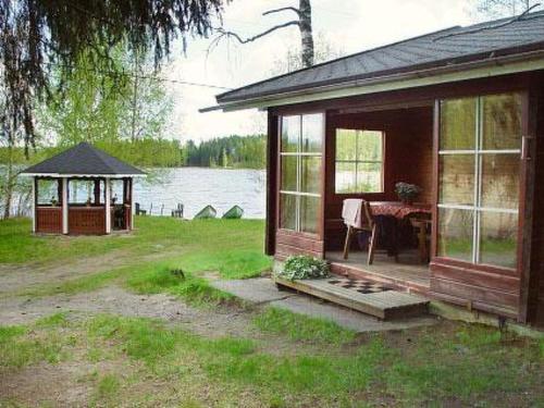 a cabin with a table and a gazebo in the yard at Holiday Home Alahuone by Interhome in Pätiälä