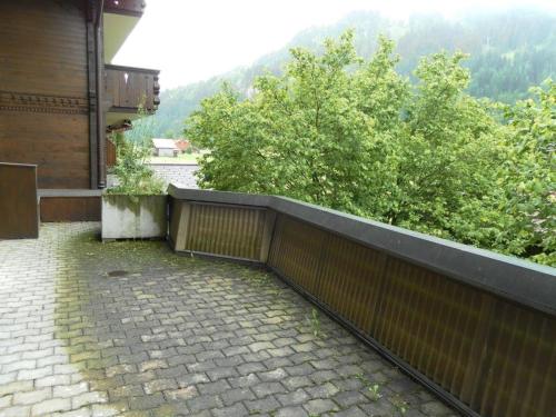 a balcony of a house with a brick sidewalk and trees at Apartment Kronenplatz 6 # 2 by Interhome in Lenk