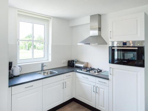 ノールトウェイケルハウトにあるHoliday Home de Witte Raaf-2 by Interhomeの白いキャビネット、シンク、窓付きのキッチン