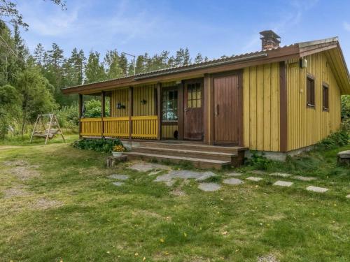 a small yellow house with a porch and a yard at Holiday Home Rantapirtti by Interhome in Niskamäki