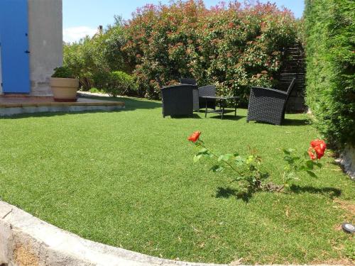 a yard with two chairs and a table and flowers at Holiday Home Les Fées-1 by Interhome in Hyères