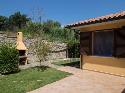 um jardim com uma parede de pedra e uma casa em Villa Serra by Interhome em Suvereto