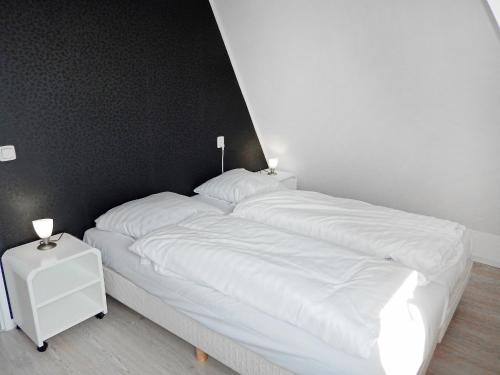 a bed with white sheets and two lamps on it at Holiday Home Plevier Comfort-3 by Interhome in Noordwijkerhout