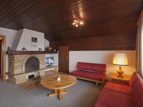 a living room with a red couch and a fireplace at Apartment Appartementhaus Zurschmitten 17 DW by Interhome in Riederalp