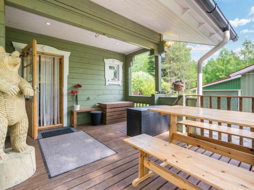 a porch with a wooden bench and a bear statue at Holiday Home Isoniemi by Interhome in Suinula