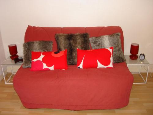 a red couch with red and white pillows at Gîte L'Ermitage in Tours