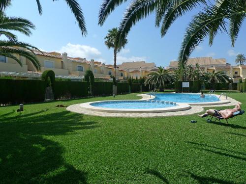 a person laying in a lawn chair next to a swimming pool at Apartment El Datiler by Interhome in Denia
