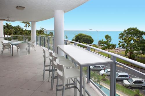 a patio area with chairs, tables, and umbrellas at Vision Apartments in Cairns