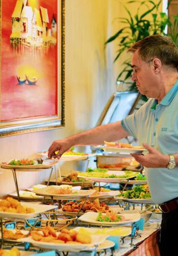a man standing at a buffet with plates of food at Hanoi Larosa Hotel in Hanoi