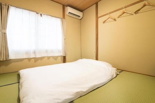 a bedroom with a white bed and a window at Yufuin Yukari-an Megumi no Sato in Yufuin