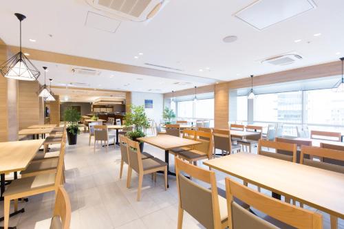 a restaurant with tables and chairs and windows at JR Kyushu Station Hotel Kokura in Kitakyushu