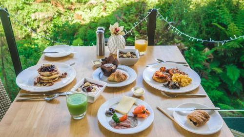 a table with plates of breakfast food on it at Legacy Te Waonui Hotel Franz Josef in Franz Josef