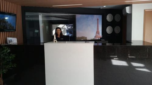 a woman standing behind a counter in a room with clocks at HOTEL EIFFEL in Ensenada