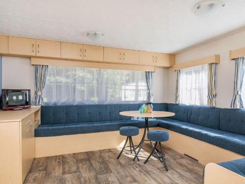 a room with blue couches and a table and a window at Holiday Home Prinsenmeer-19 by Interhome in De Beek