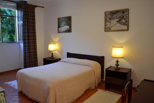 a bedroom with a bed and two lamps on tables at Casa da Ponte in Alvoco da Serra