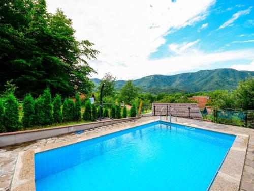 a large blue swimming pool with mountains in the background at Holiday Home Božica by Interhome in Brod na Kupi