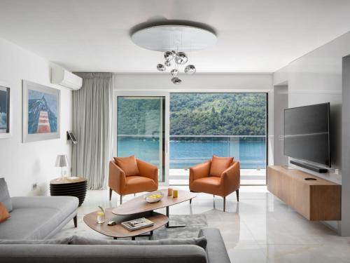 ein Wohnzimmer mit einem Sofa und Stühlen sowie einem großen Fenster in der Unterkunft Villa Vlastelini II by Interhome in (( Hrvatini ))