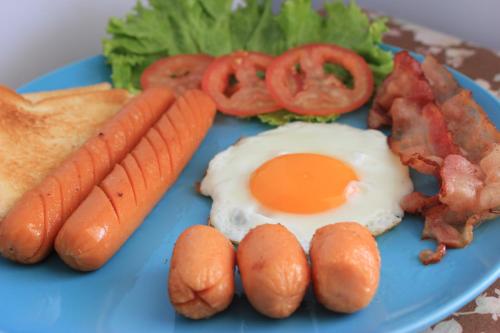 un piatto blu di cibo con uova, pancetta e verdure di Baan Rabiengkao Hua Hin a Hua Hin