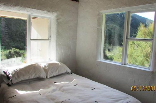 - un lit dans une chambre avec 2 fenêtres dans l'établissement Provence Cottage, à Carterton