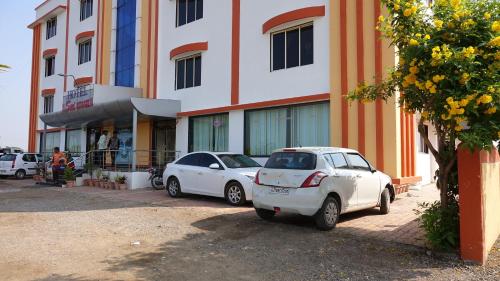 two cars parked in front of a building at Hotel Sai Shraddha in Shirdi