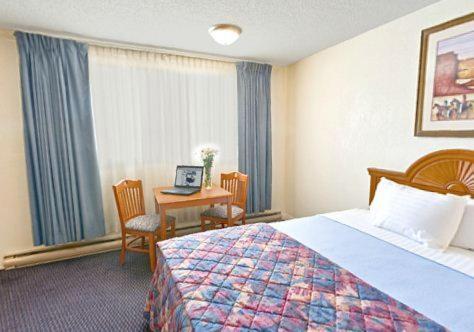 a hotel room with a bed and a desk with a laptop at Casa Lemus Inn in Raton