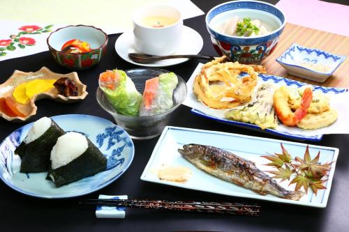 a table topped with plates of food with fish and vegetables at Tubakiann in Kikuchi
