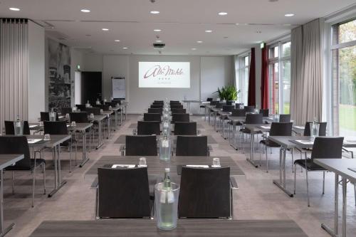 a conference room with tables and chairs and a screen at Privathotel alte mühle Wolfsburg-Weyhausen in Wolfsburg