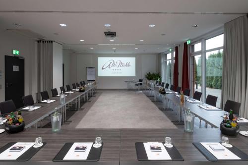 a conference room with long tables and chairs and a screen at Privathotel alte mühle Wolfsburg-Weyhausen in Wolfsburg