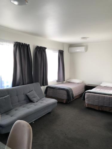 a living room with two beds and a couch at Grosvenor Motel in Hamilton