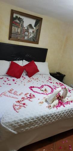 a bed with red pillows and a stuffed animal on it at Hotel Real Antigua in Antigua Guatemala