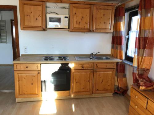 a kitchen with wooden cabinets and a sink and a stove at Bauernhaus Auberg in Hutthurm