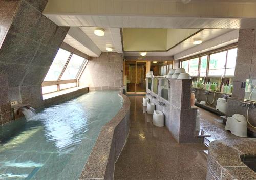 baño grande con piscina grande en Hotel Sambancho, en Matsuyama